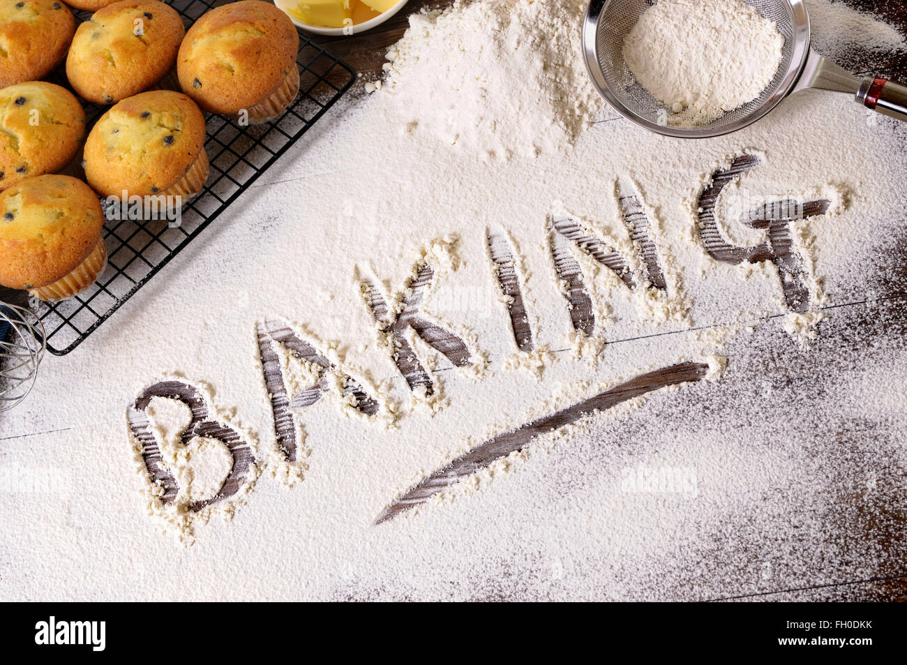 The word Baking written in flour on a dark wood table with freshly