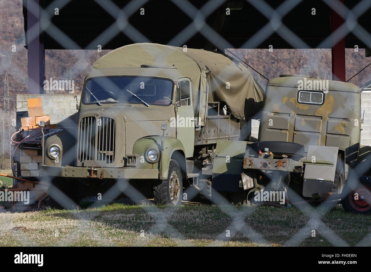 Old military transport truck behind a chain link fence at an army depot