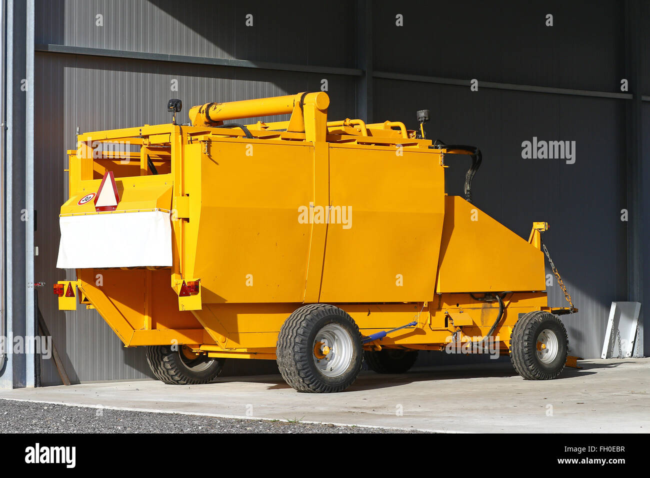 Yellow agricultural tow compactor for baling grass Stock Photo