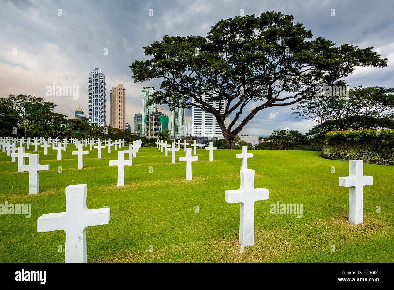 Graves and modern buildings in the distance at the Manila American Cemetery & Memorial, in Taguig, Metro Manila, The Philippines Stock Photo