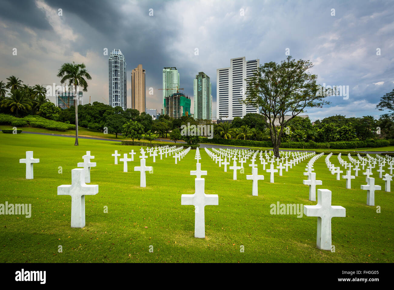 Graves and modern buildings in the distance at the Manila American Cemetery & Memorial, in Taguig, Metro Manila, The Philippines Stock Photo
