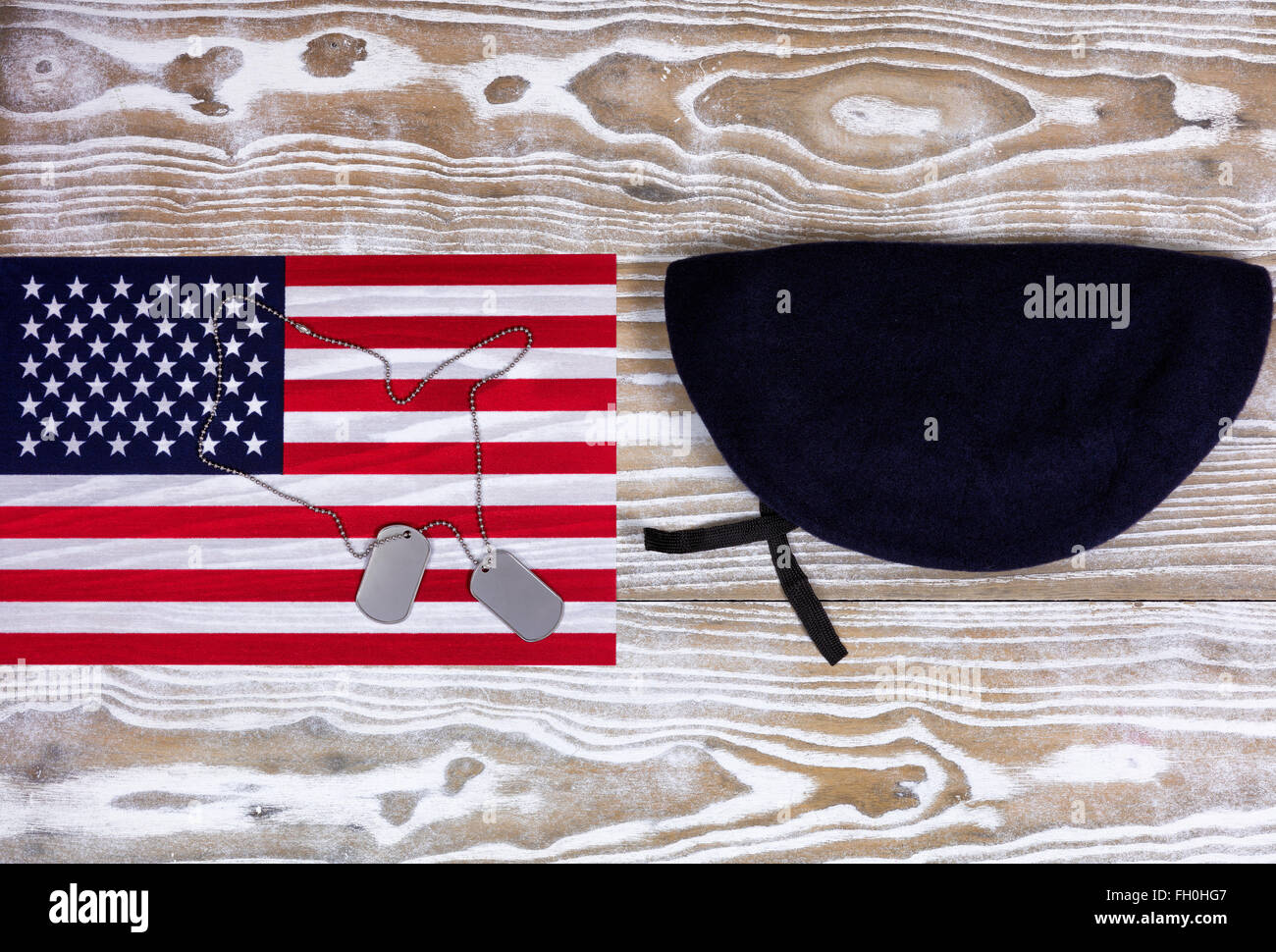 Overhead view of a United of America flag, ID tags, and beret on faded white wood. Stock Photo