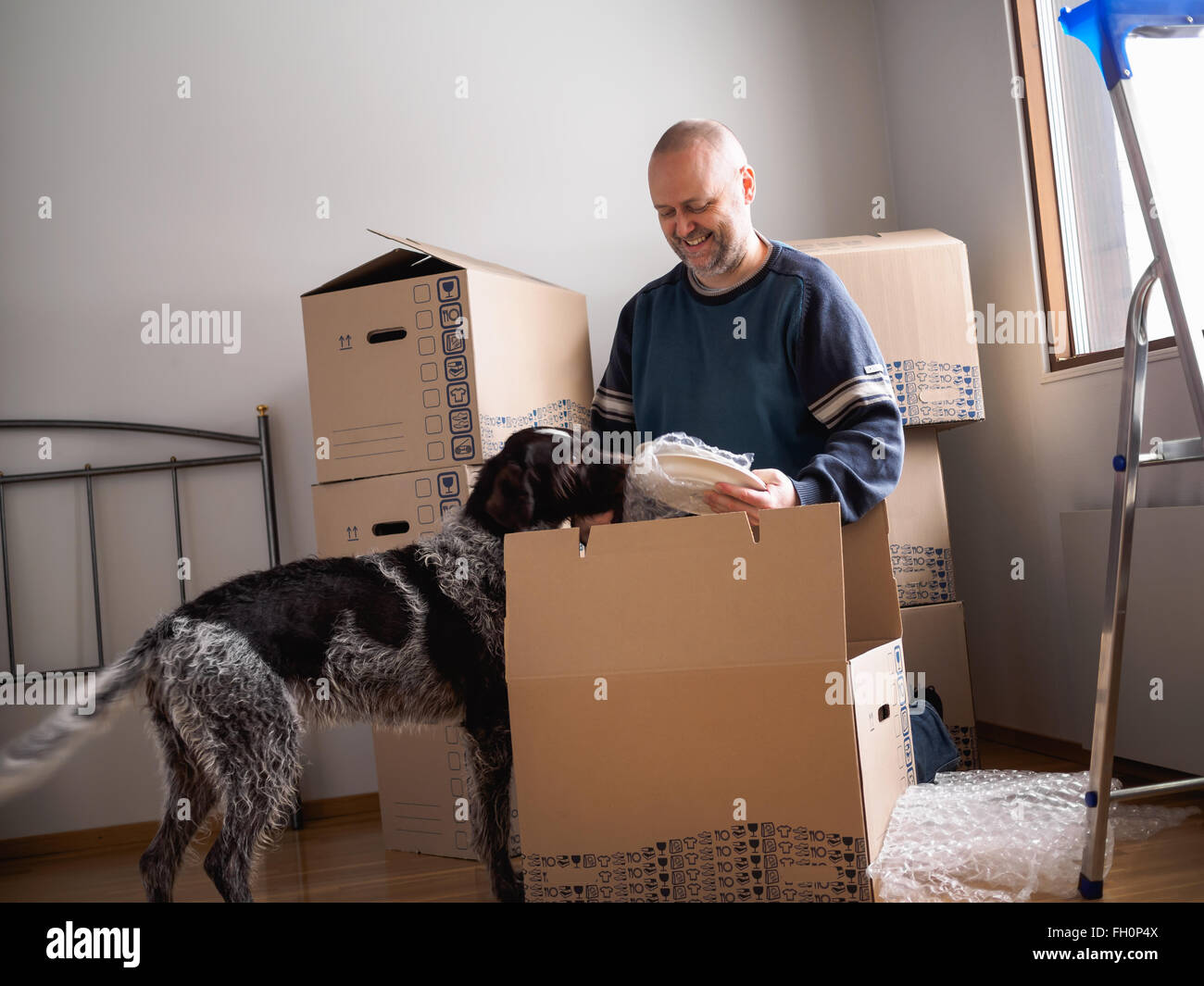 People moving house, man packing plates Stock Photo