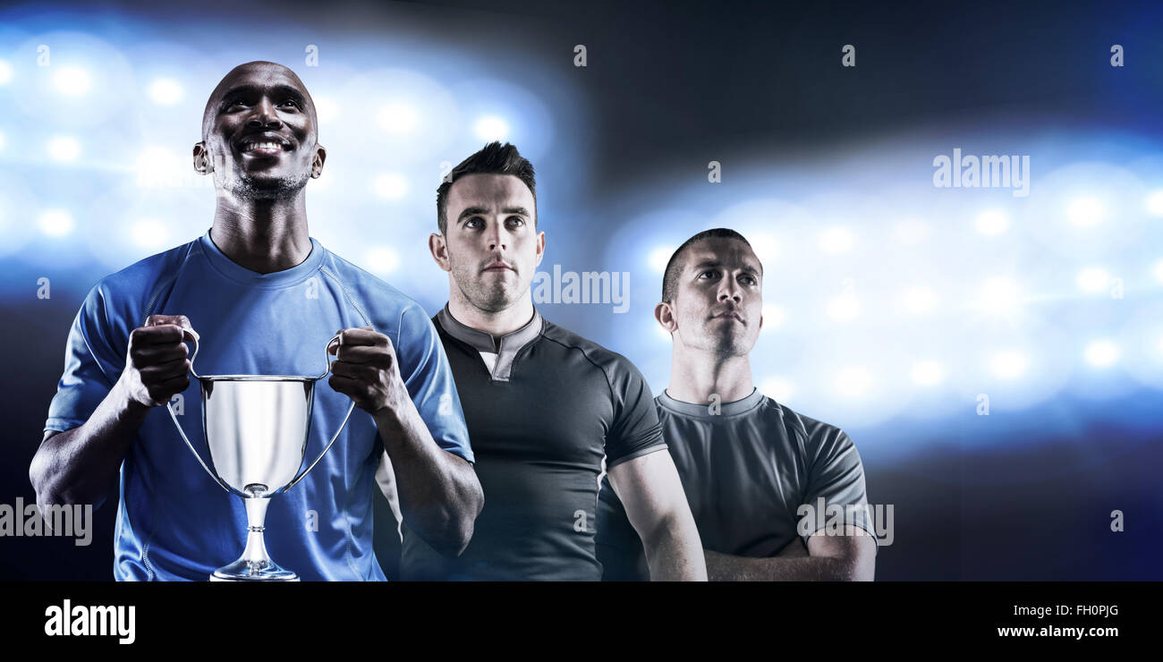 Composite image of happy athlete holding trophy looking up Stock Photo