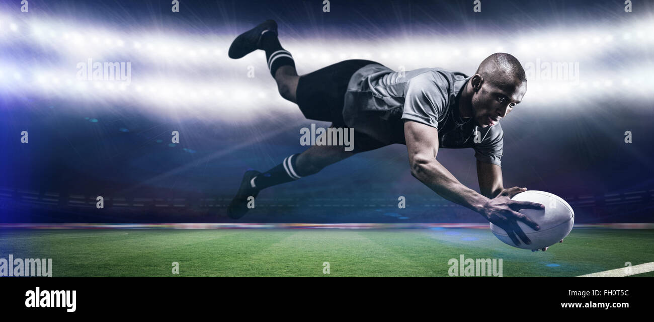 Composite image of sportsman jumping for catching rugby ball Stock ...