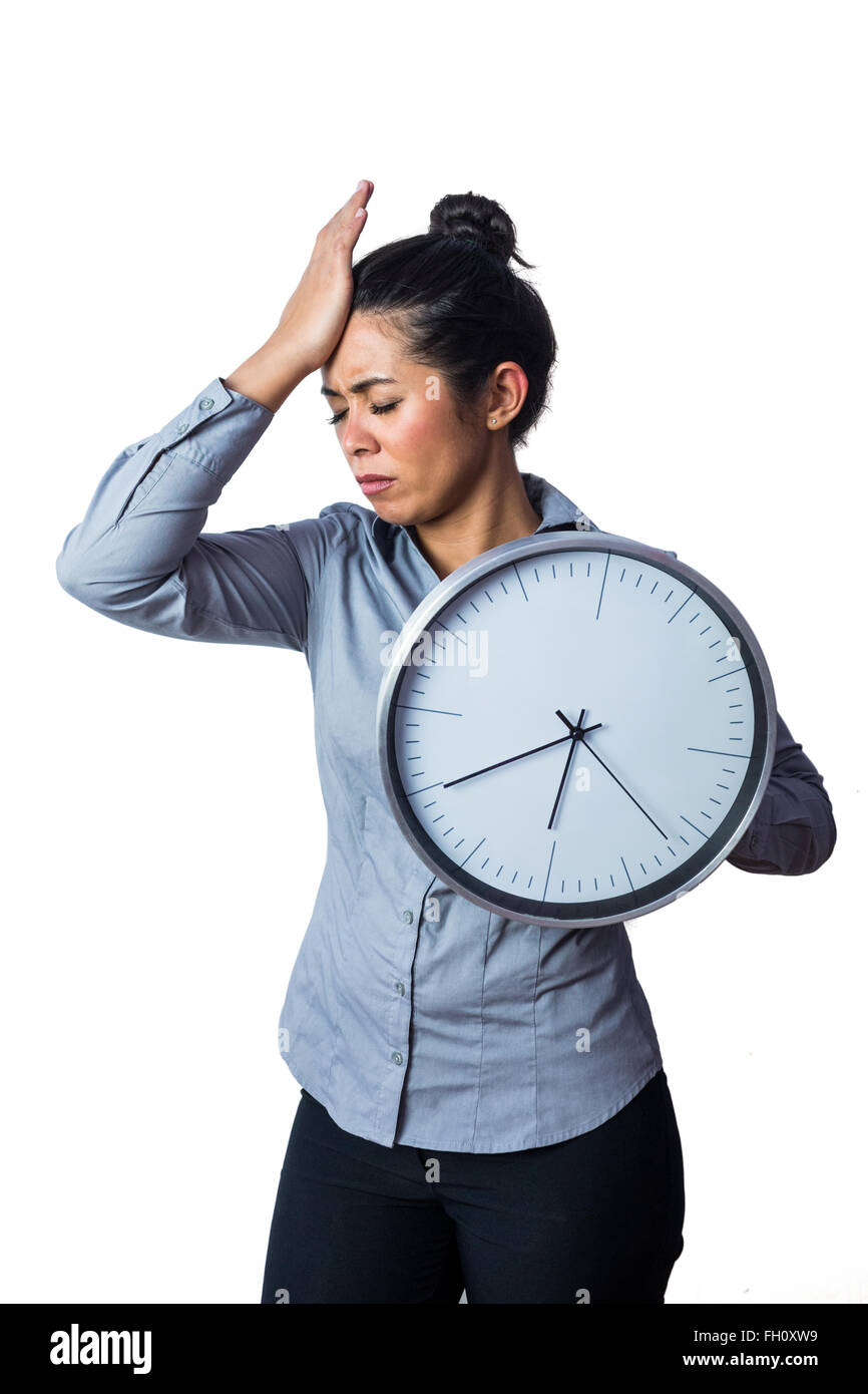Woman slapping her forehead and holding a clock Stock Photo