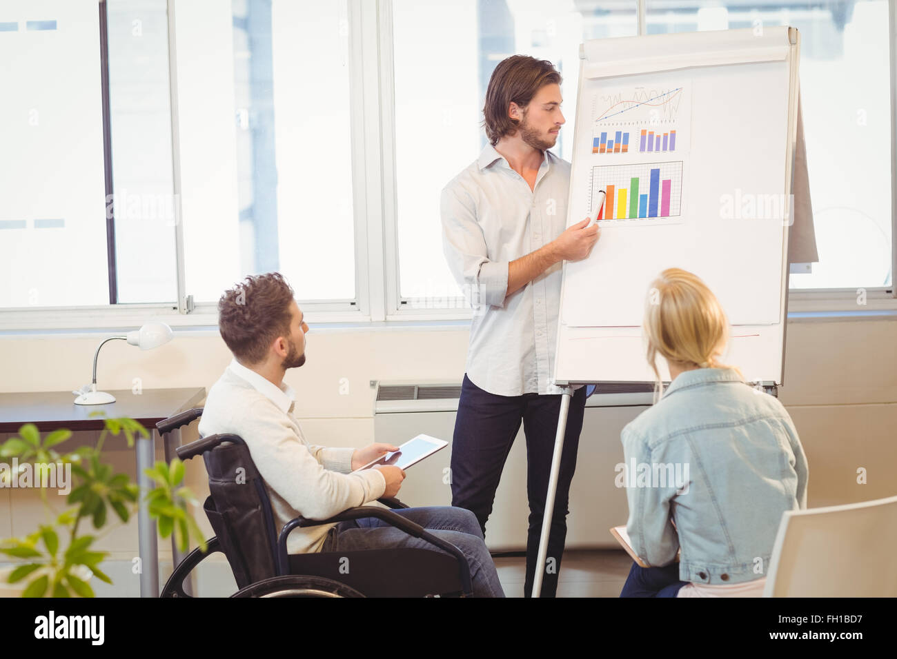 Businessman explaining multi colored graph to colleagues Stock Photo ...