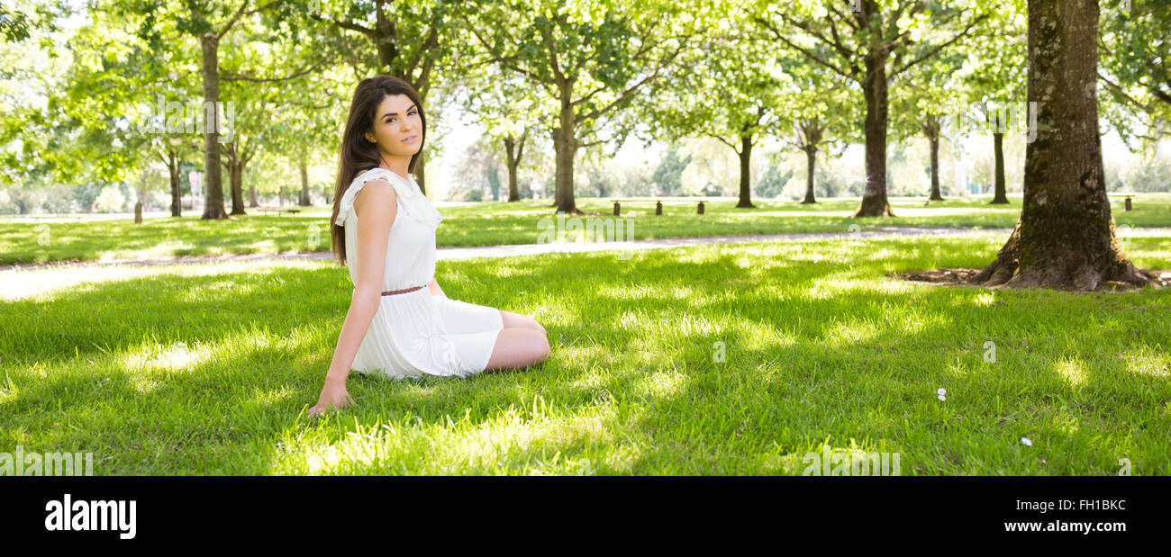 Young woman sitting on grassland in park Stock Photo - Alamy