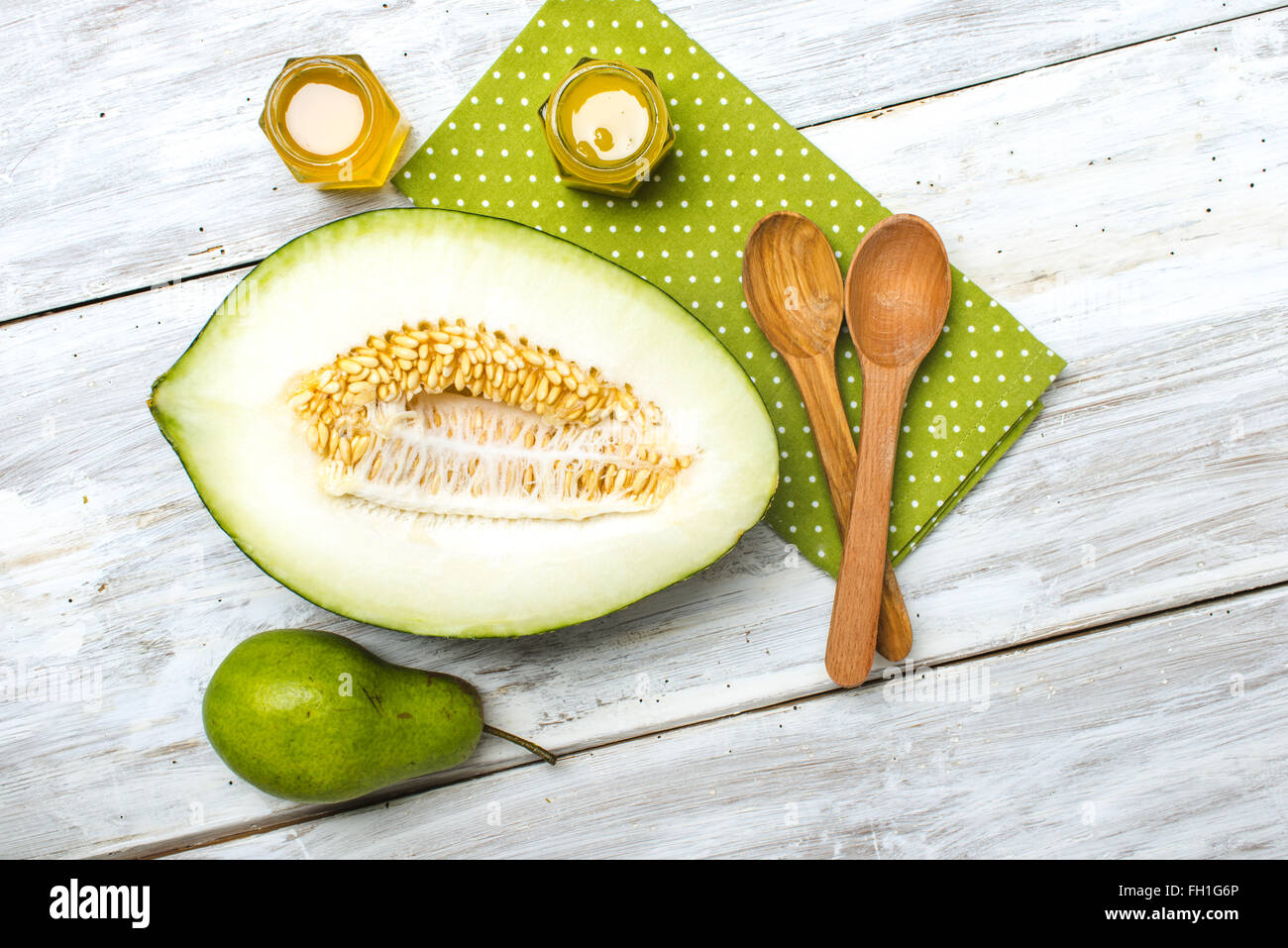 Cut melon honey and green pear on wooden board in rustic style Stock Photo