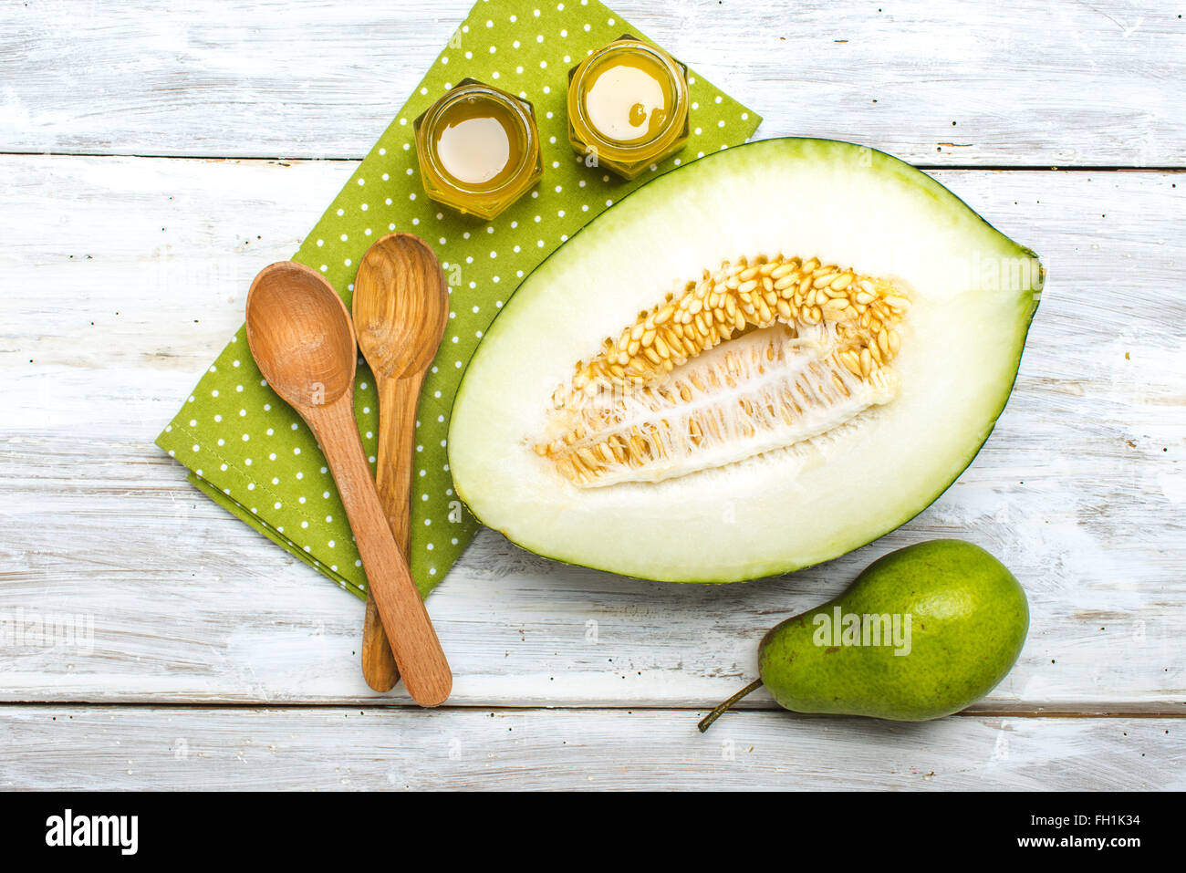 Cut melon green pear and honey on white board in rustic style Stock Photo