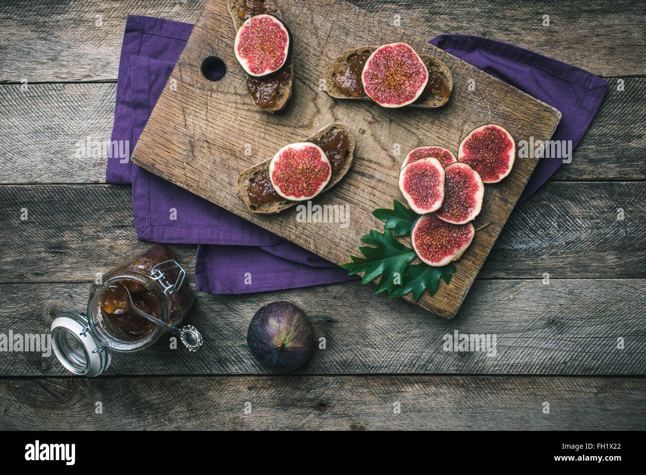 Cut figs and bread with jam on choppingboard in rustic style. Autumn season food photo Stock Photo