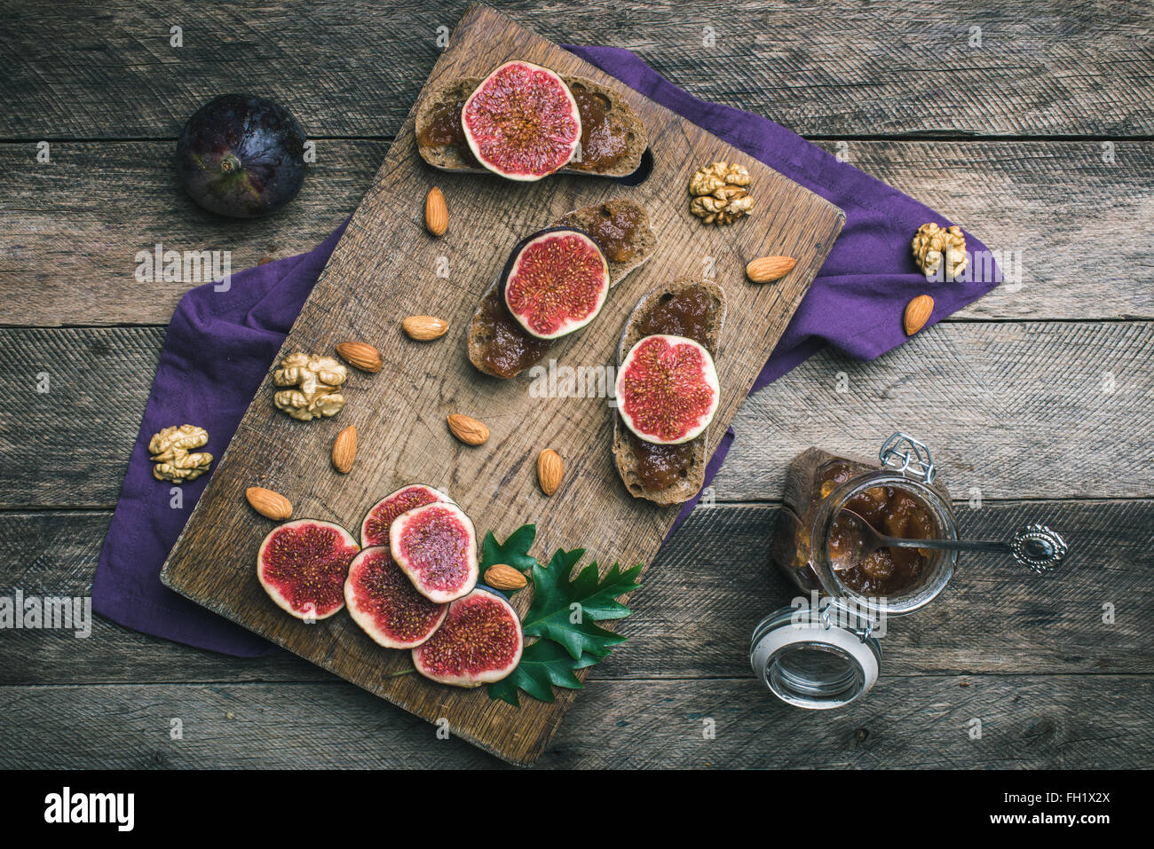 figs, nuts and bread with jam on choppingboard in rustic style. Autumn season food photo Stock Photo