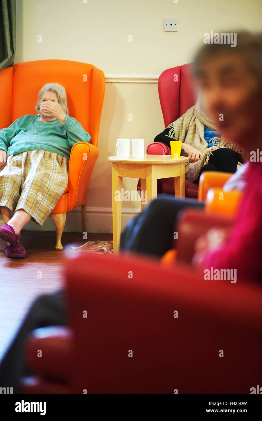 elderly women in a dementia unit in a health and social care nursing home sit in the day room Stock Photo