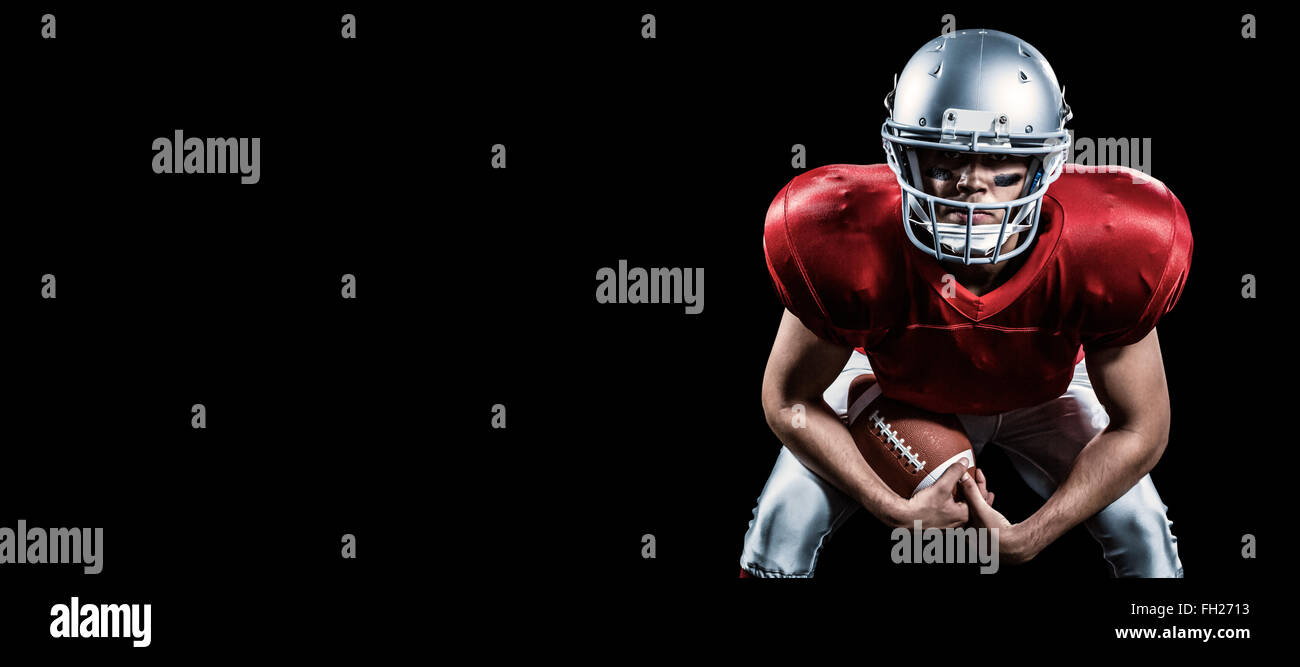 Composite image of portrait of american football player bending while holding ball Stock Photo