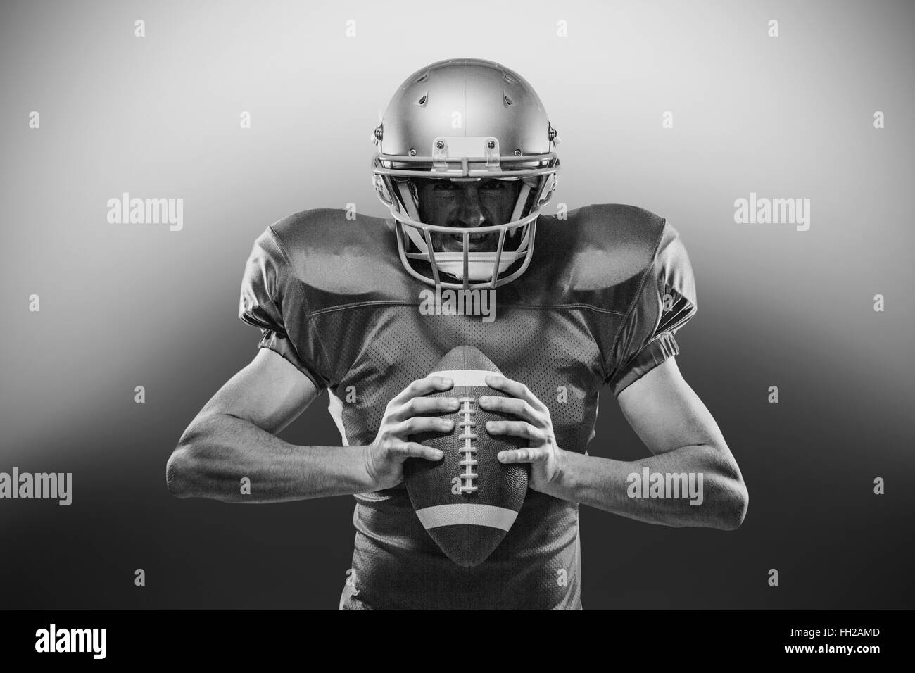 American football player in red jersey and helmet holding ball Stock Photo