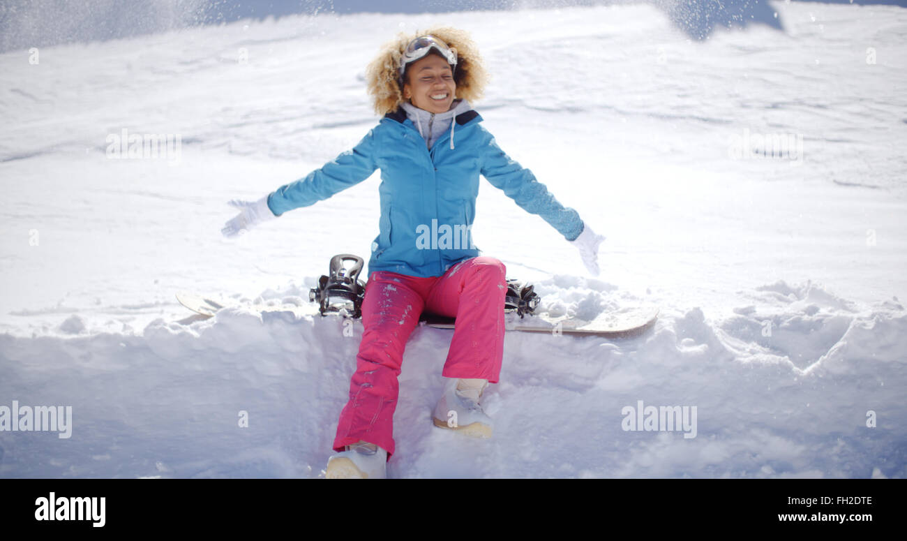 Beautiful young snowboarder sitting on snow Stock Photo