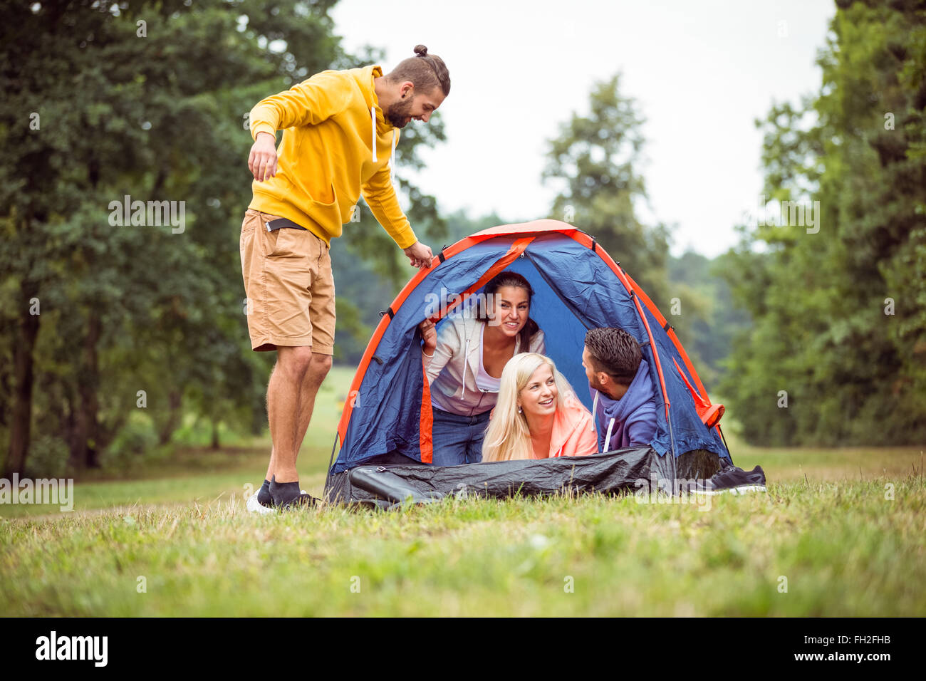 Happy friends setting up their tent Stock Photo - Alamy