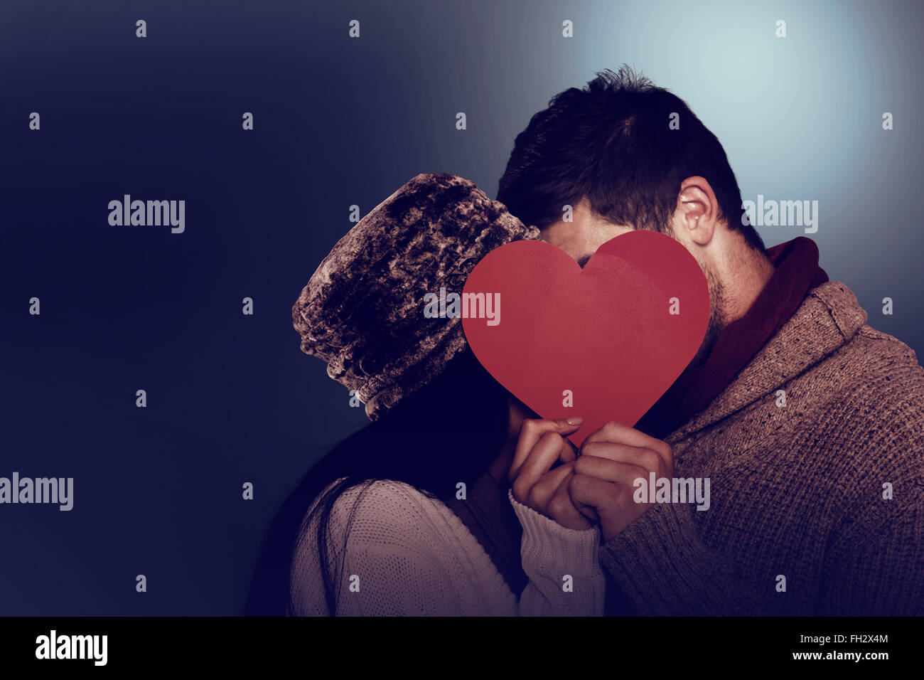 Young couple kissing behind red heart Stock Photo - Alamy