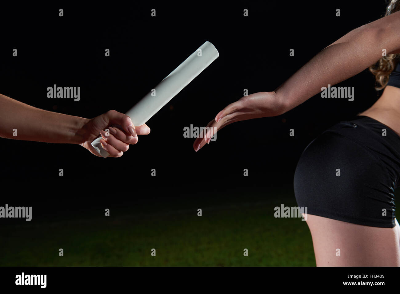 athletic runners passing baton in relay race Stock Photo