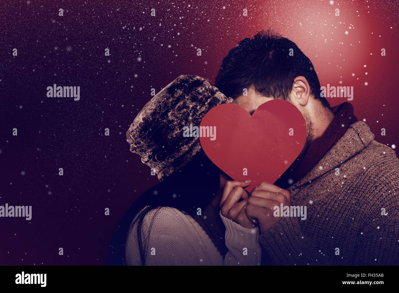 Composite image of young couple kissing behind red heart Stock Photo ...