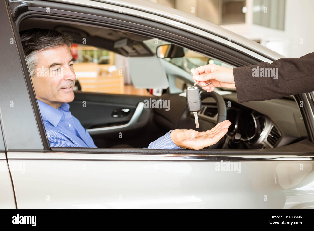 Salesman giving keys to a smiling businessman Stock Photo - Alamy