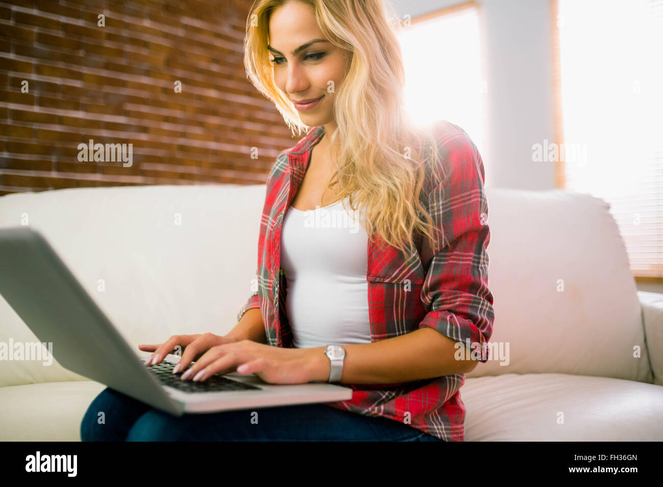 Pretty blonde using laptop on couch Stock Photo