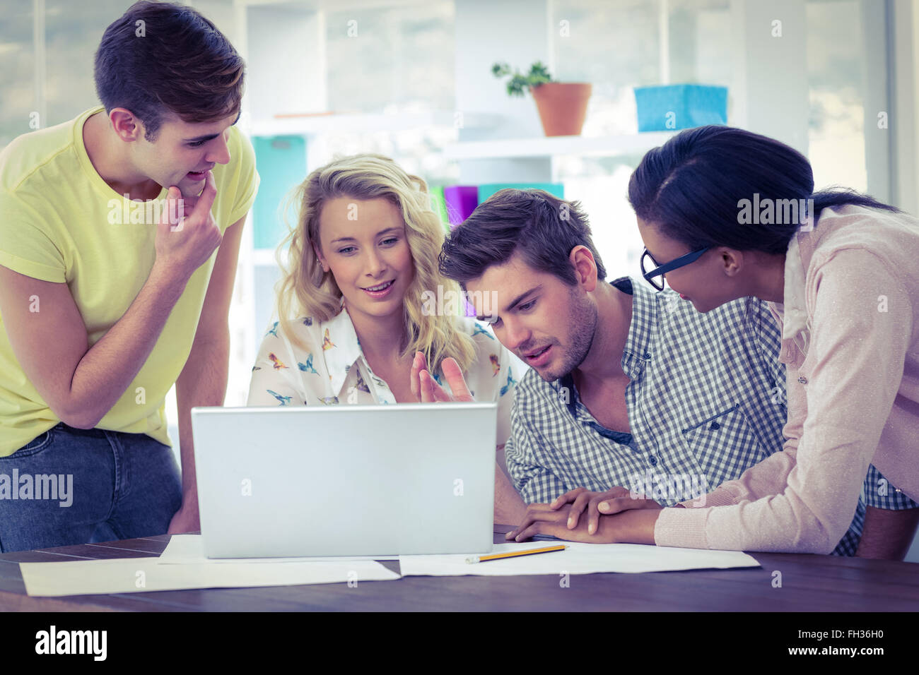 Creative business team working on a laptop together Stock Photo - Alamy