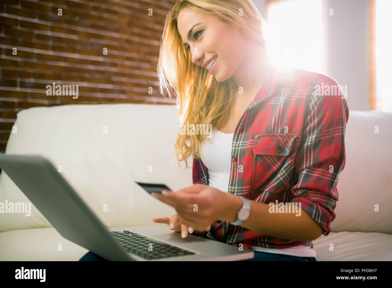 Pretty blonde using laptop on couch Stock Photo