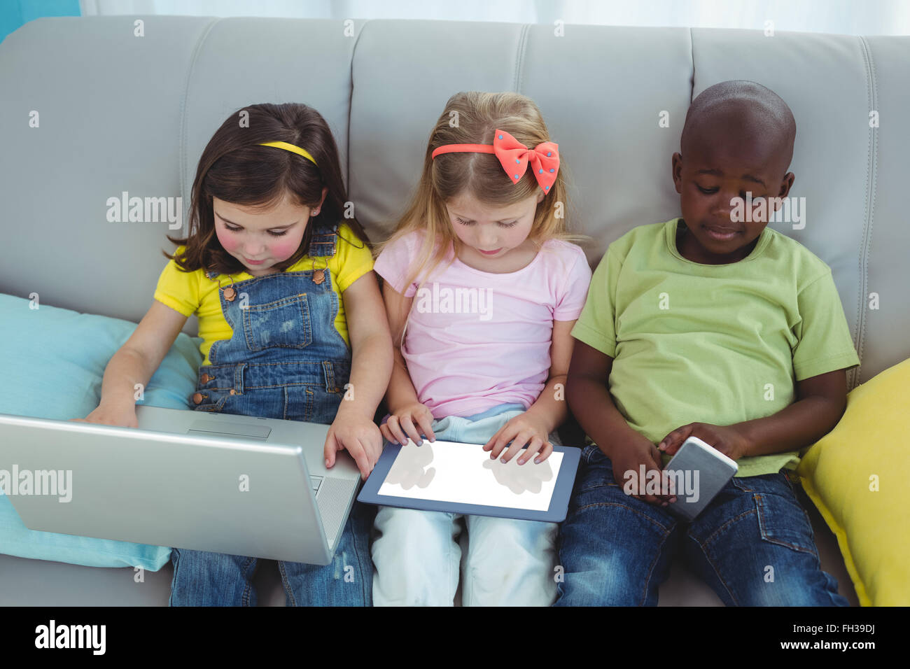 Happy kids sitting together with a tablet Stock Photo - Alamy