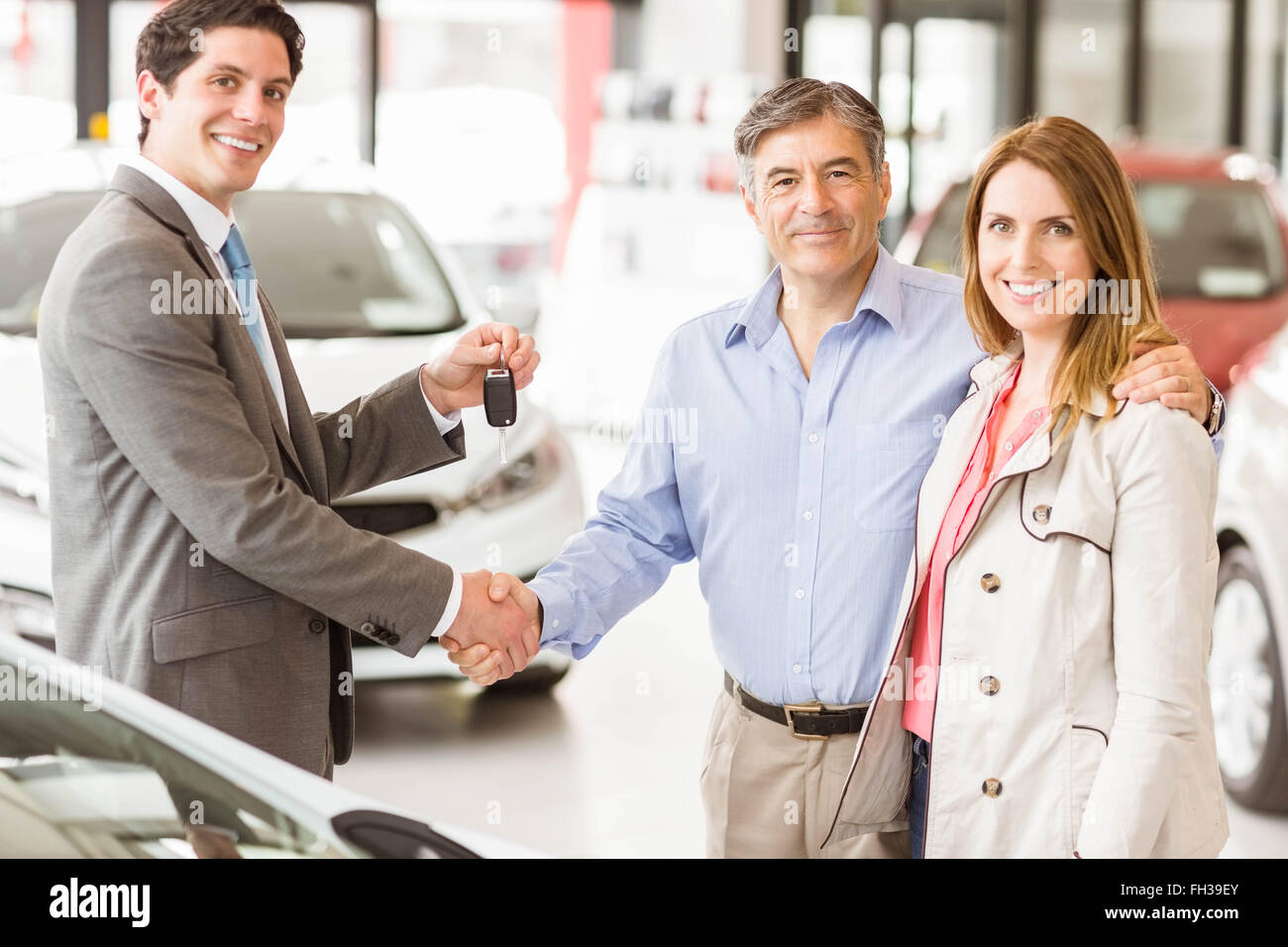 Salesman giving car key to a couple Stock Photo - Alamy