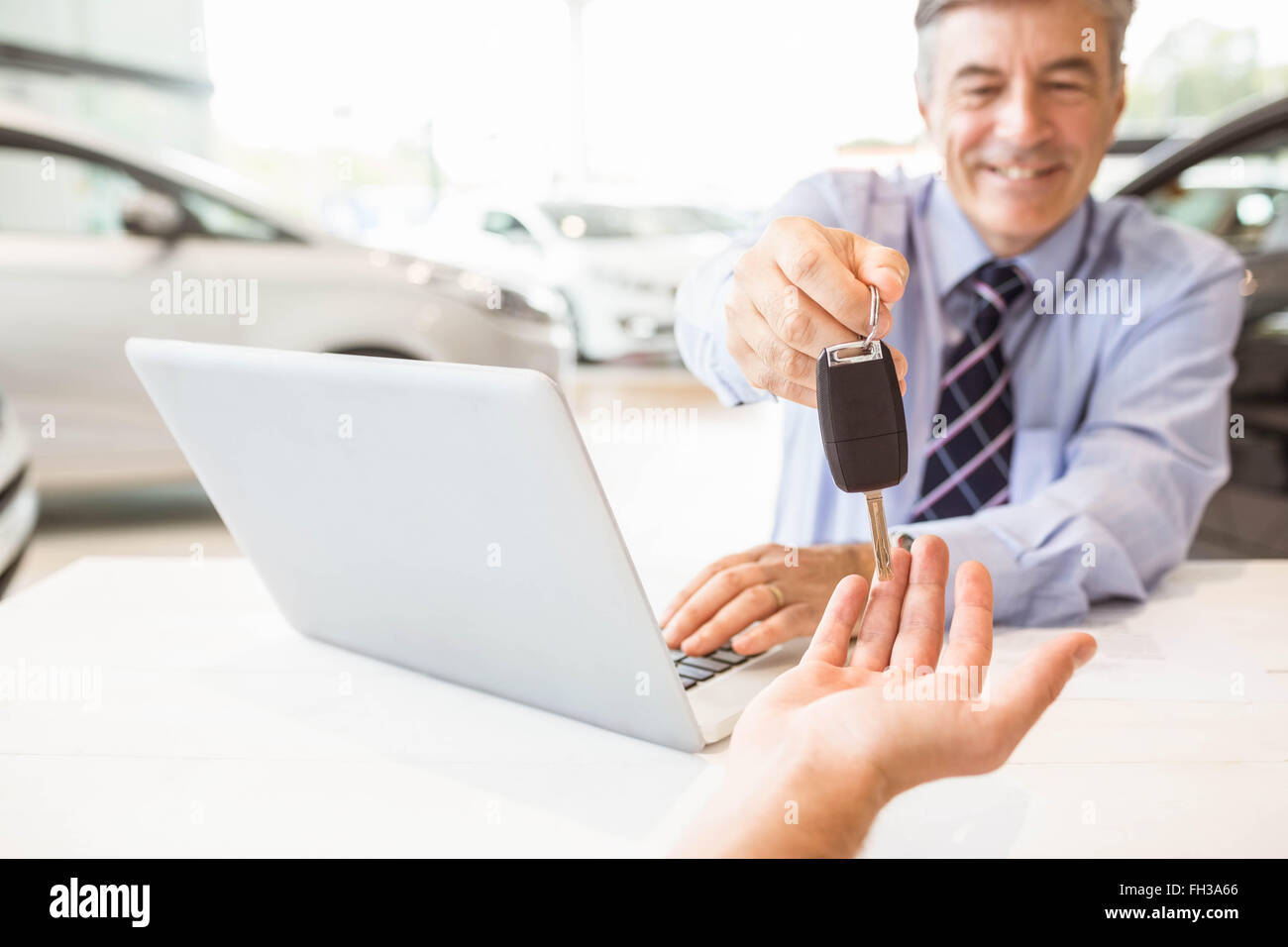 Smiling salesman holding a customer car key Stock Photo - Alamy