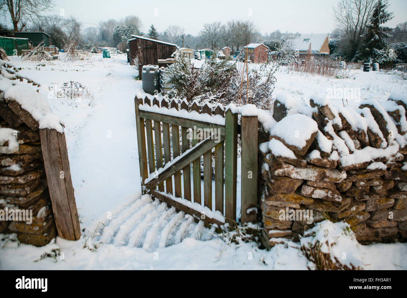 A snow covered allotment in the cotswlds, Uk that is accessed by entering through a gate set in a traditional dry stone wall common to the area. Stock Photo