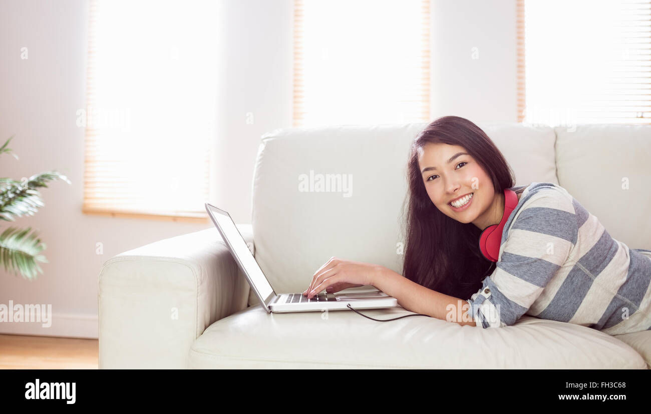 Smiling asian woman on couch using laptop Stock Photo - Alamy