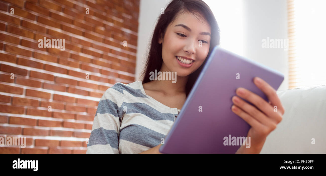 Smiling asian woman using tablet on couch Stock Photo - Alamy