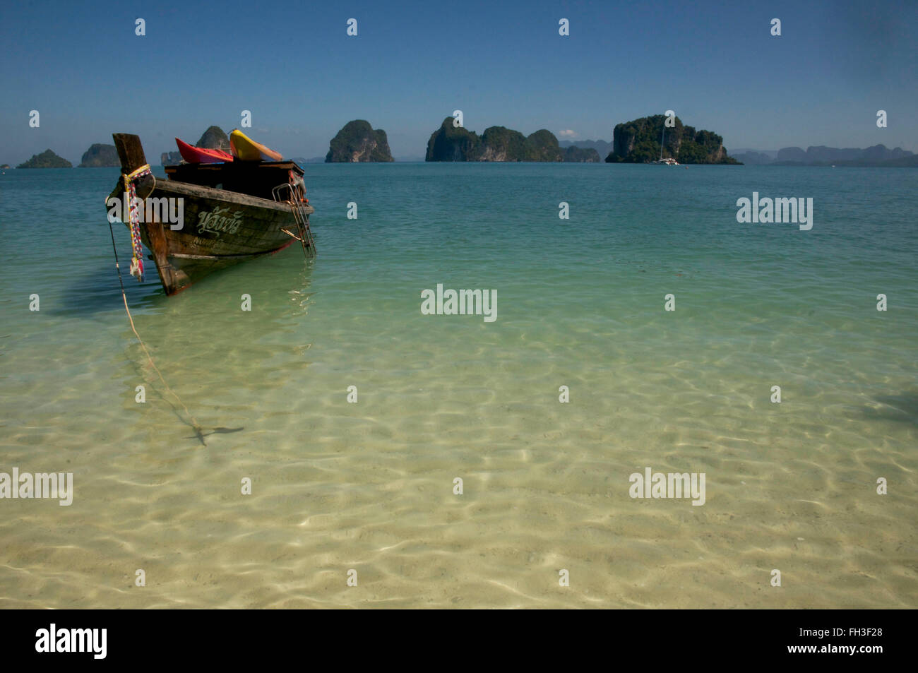 Longtail boat with kayaks strapped to top, moored on tropical beach Stock Photo