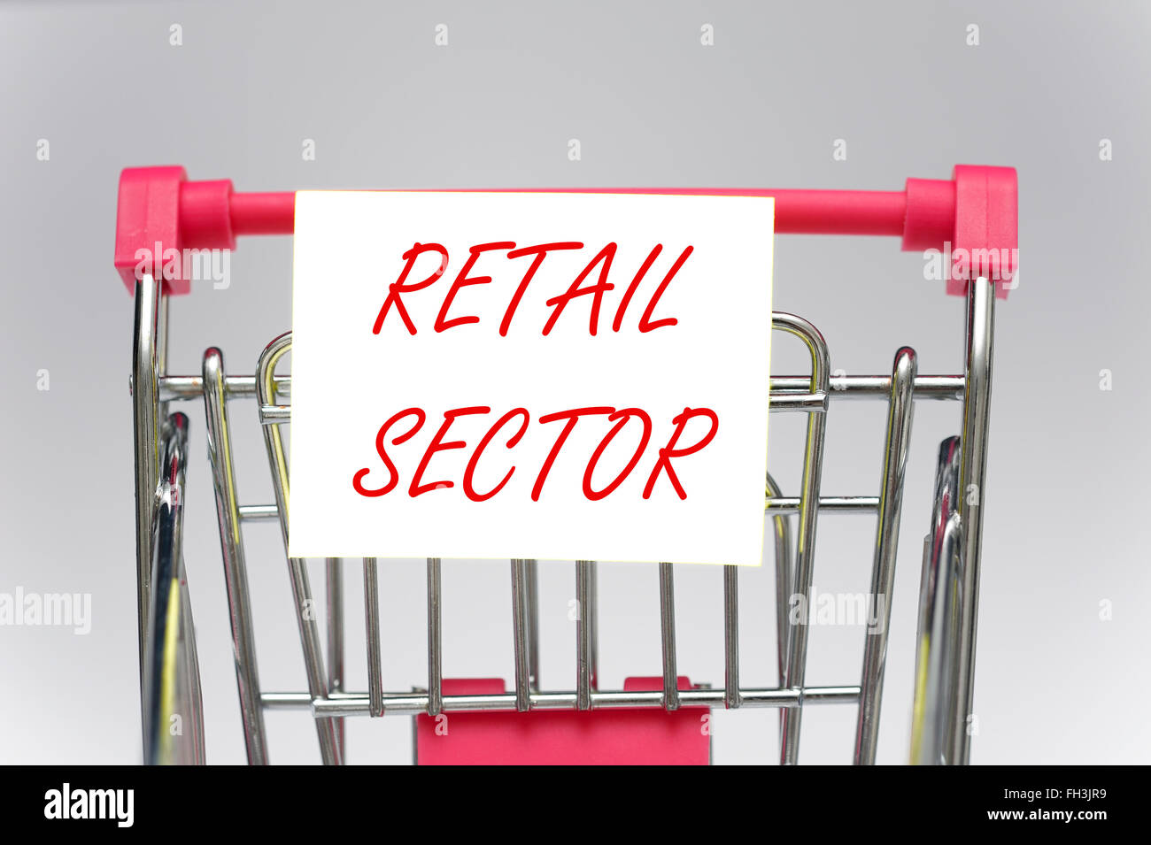 A miniature shopping trolley with retail sector sign on Stock Photo