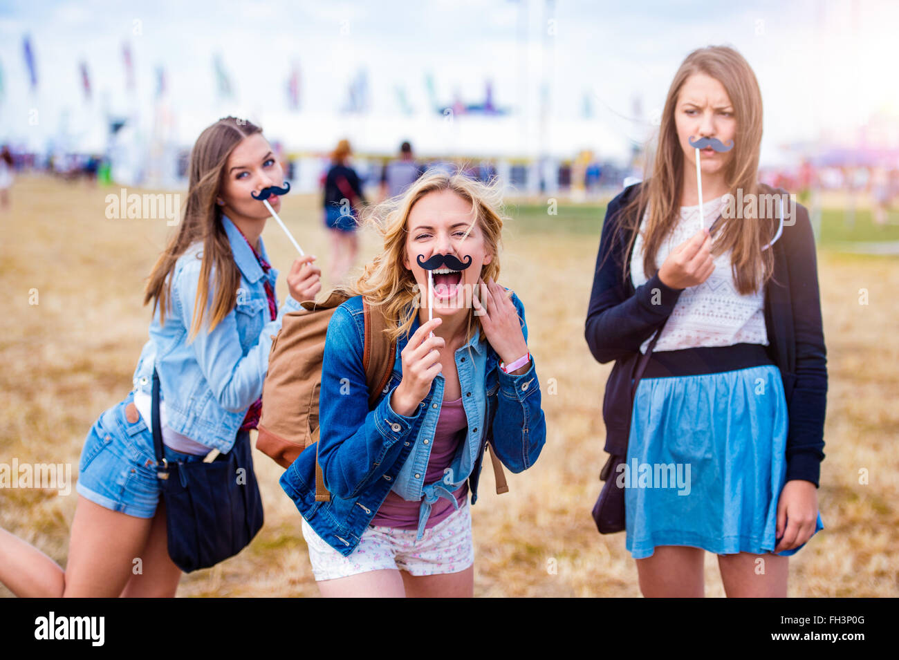 Teenage girls at summer festival with fake mustache Stock Photo