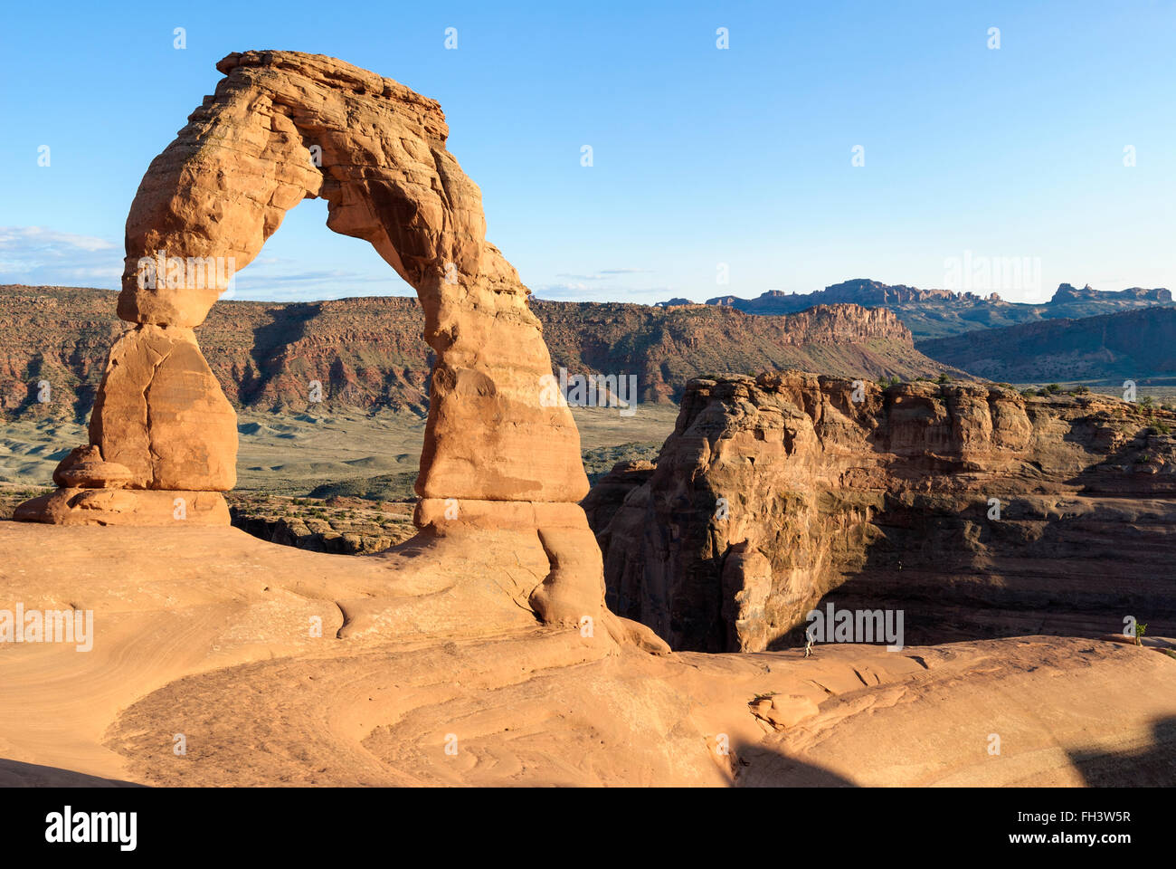 A tourist walks towards Delicate Arch in Arches National Park, Utah, USA Stock Photo