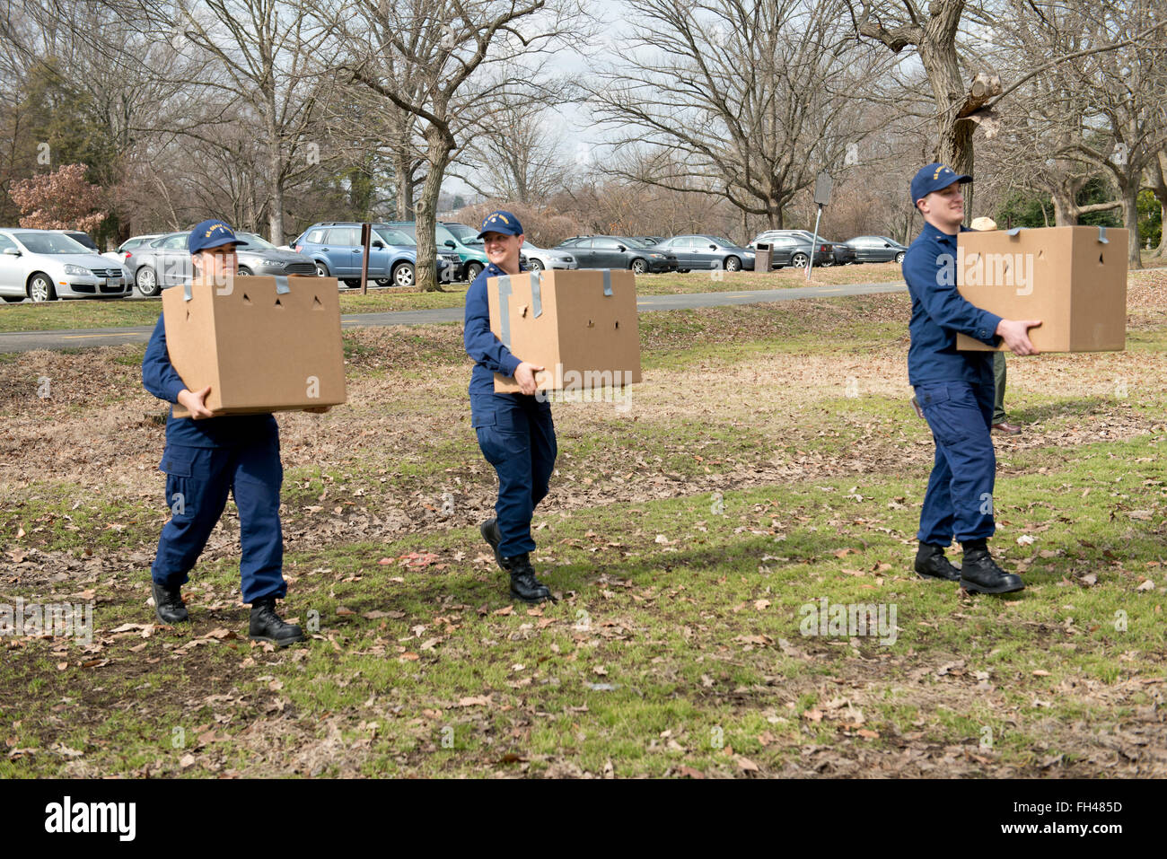 Lt. j.g. Karinne Merical, Petty Officer 3rd Class Laurel Siegrist and Petty Officer 3rd Class Christopher Worth, members the incident management division at Coast Guard Sector Baltimore, carry boxes containing rehabilitated Canada geese near Belle Haven Marina in Alexandria, Va., Monday, Feb. 22, 2016. The geese were released into the wild after being rehabilitated by Tri-State Bird Rescue and Research. Stock Photo