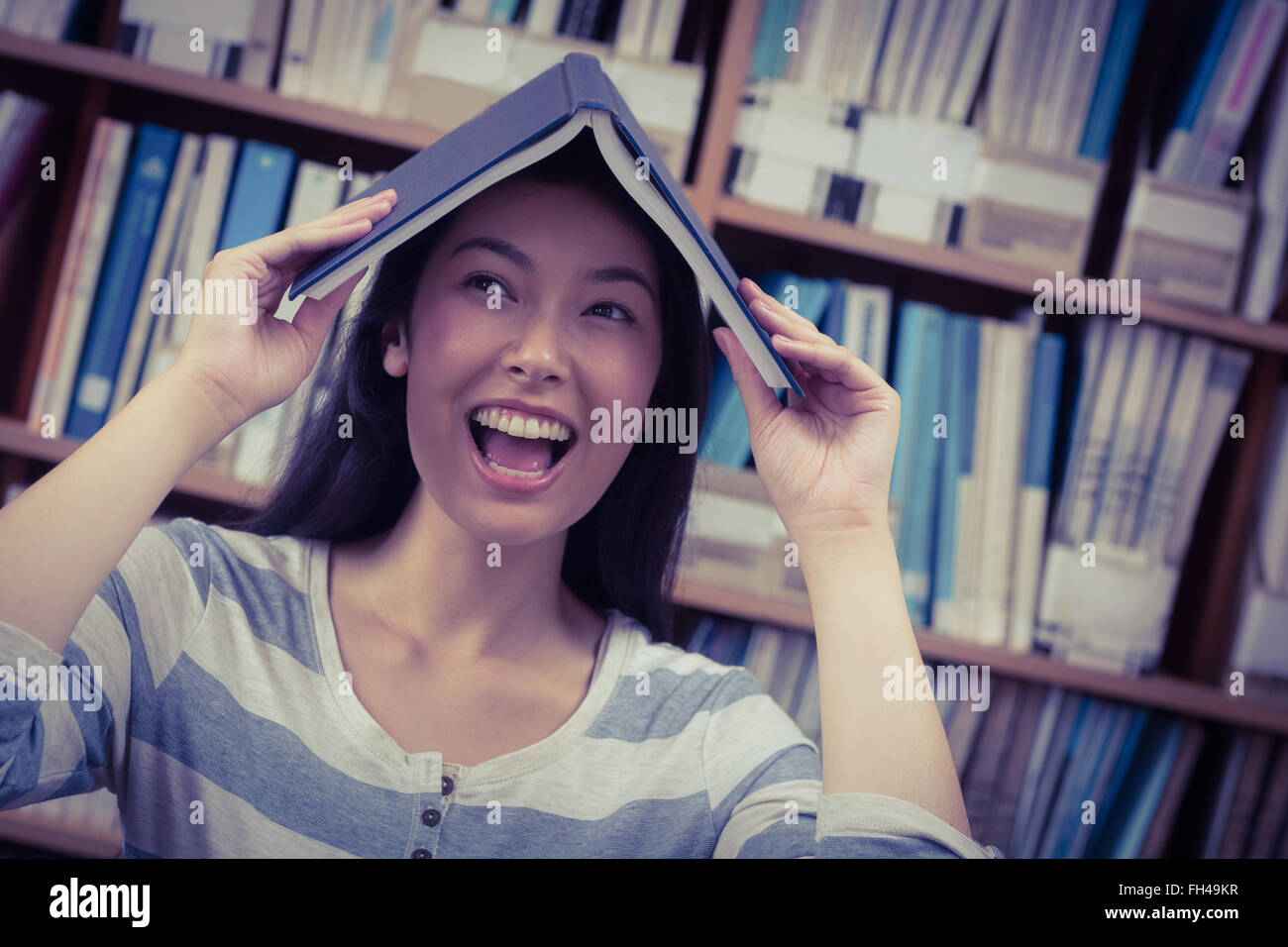Funny student holding book on her head Stock Photo - Alamy