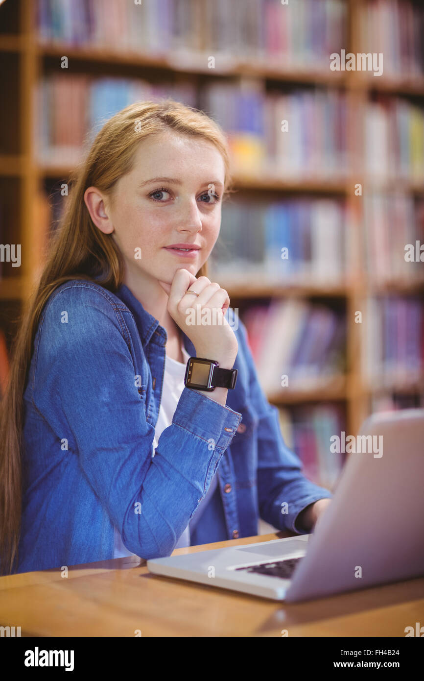 Student with smartwatch using laptop in library Stock Photo