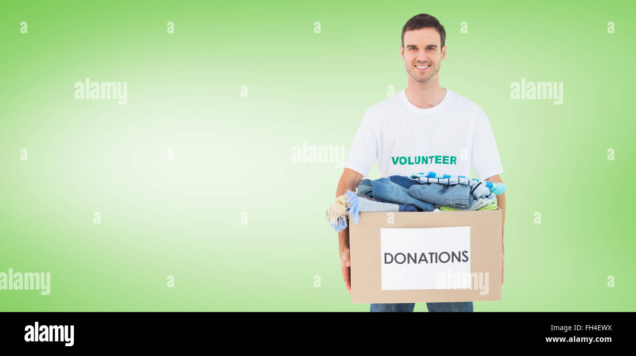 Composite image of attractive man holding donation box with clothes Stock Photo