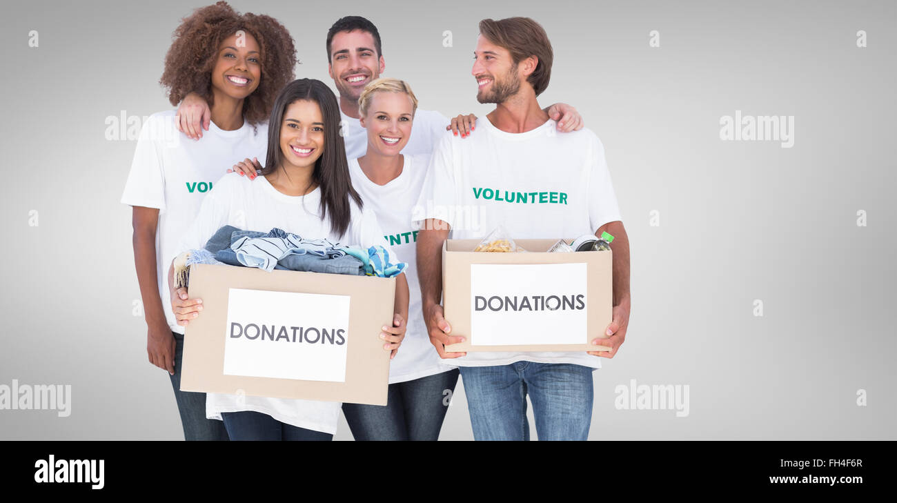 Composite image of happy group of volunteers holding clothes donation boxes Stock Photo