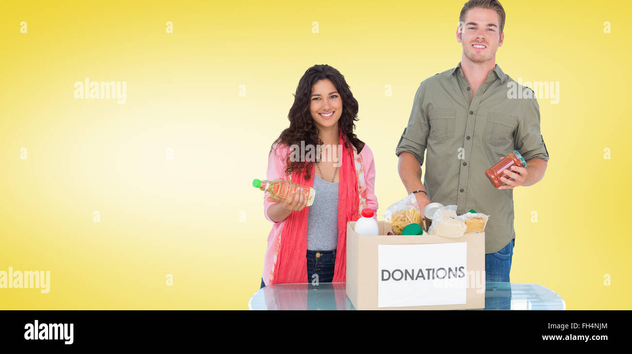 Composite image of smiling volunteers taking out food from donations box Stock Photo
