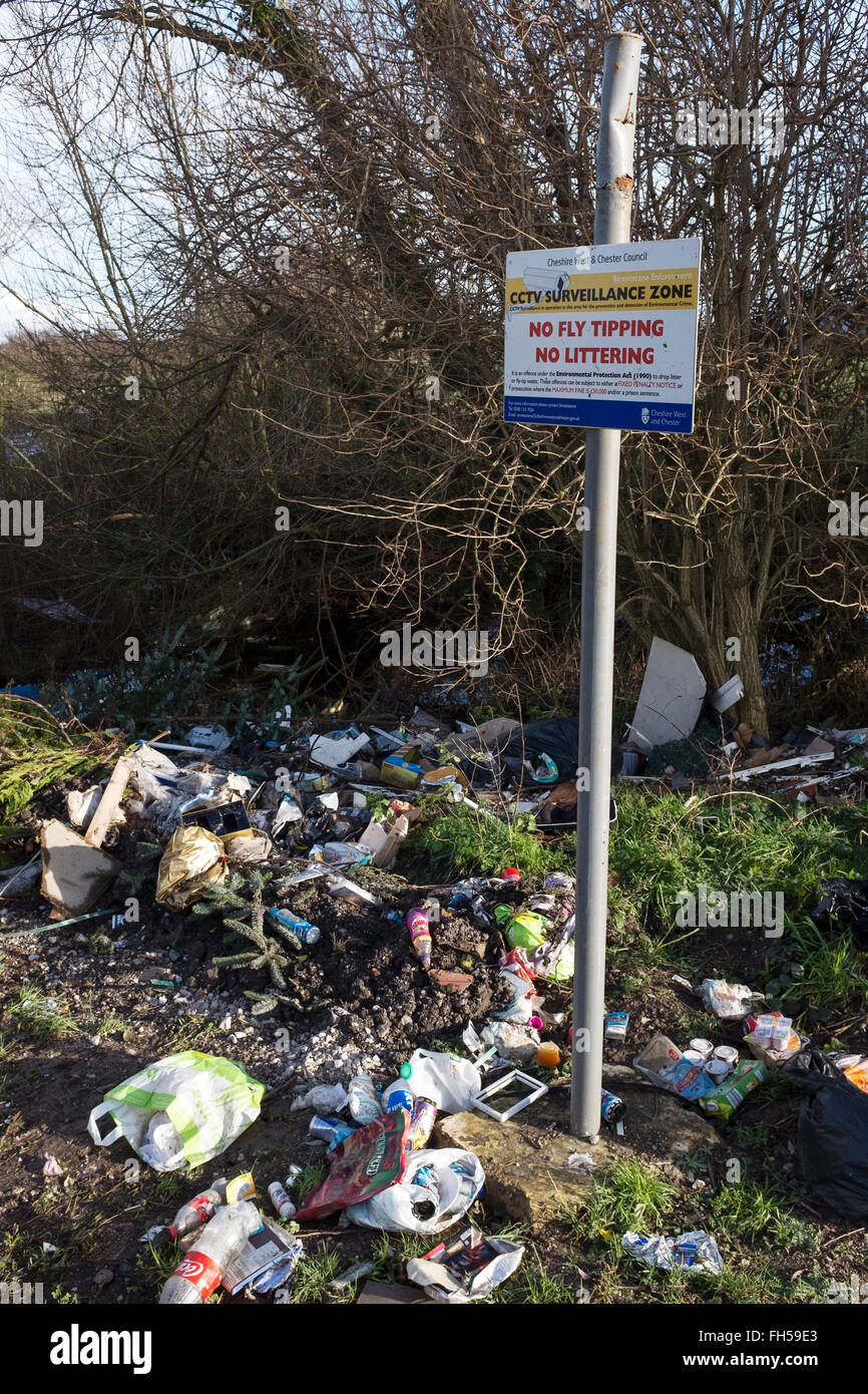 Fly tipping rubbish dumped in the countryside alongside a warning notice Stock Photo