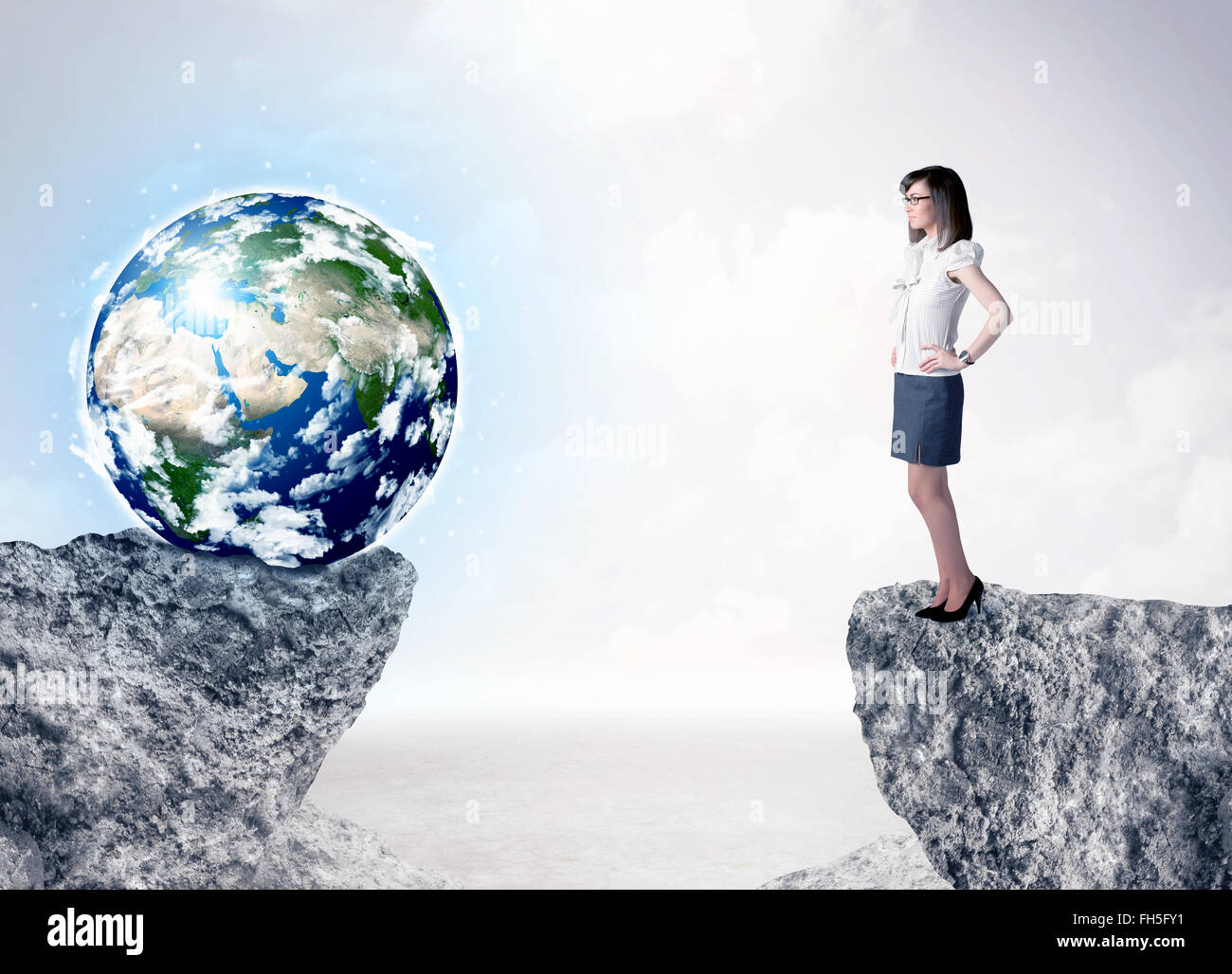 Businesswoman on rock mountain with a globe Stock Photo