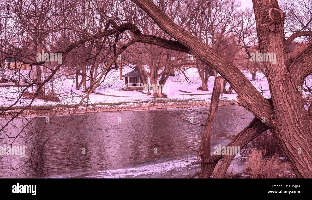 Across the River - Rural winter landscape with slow-flowing river and garden gazebo across the river Stock Photo