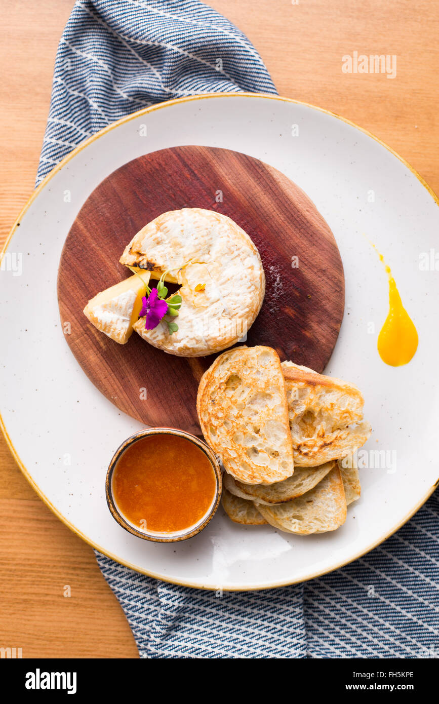An overhead view of brie cheese with crostini and a red dipping sauce