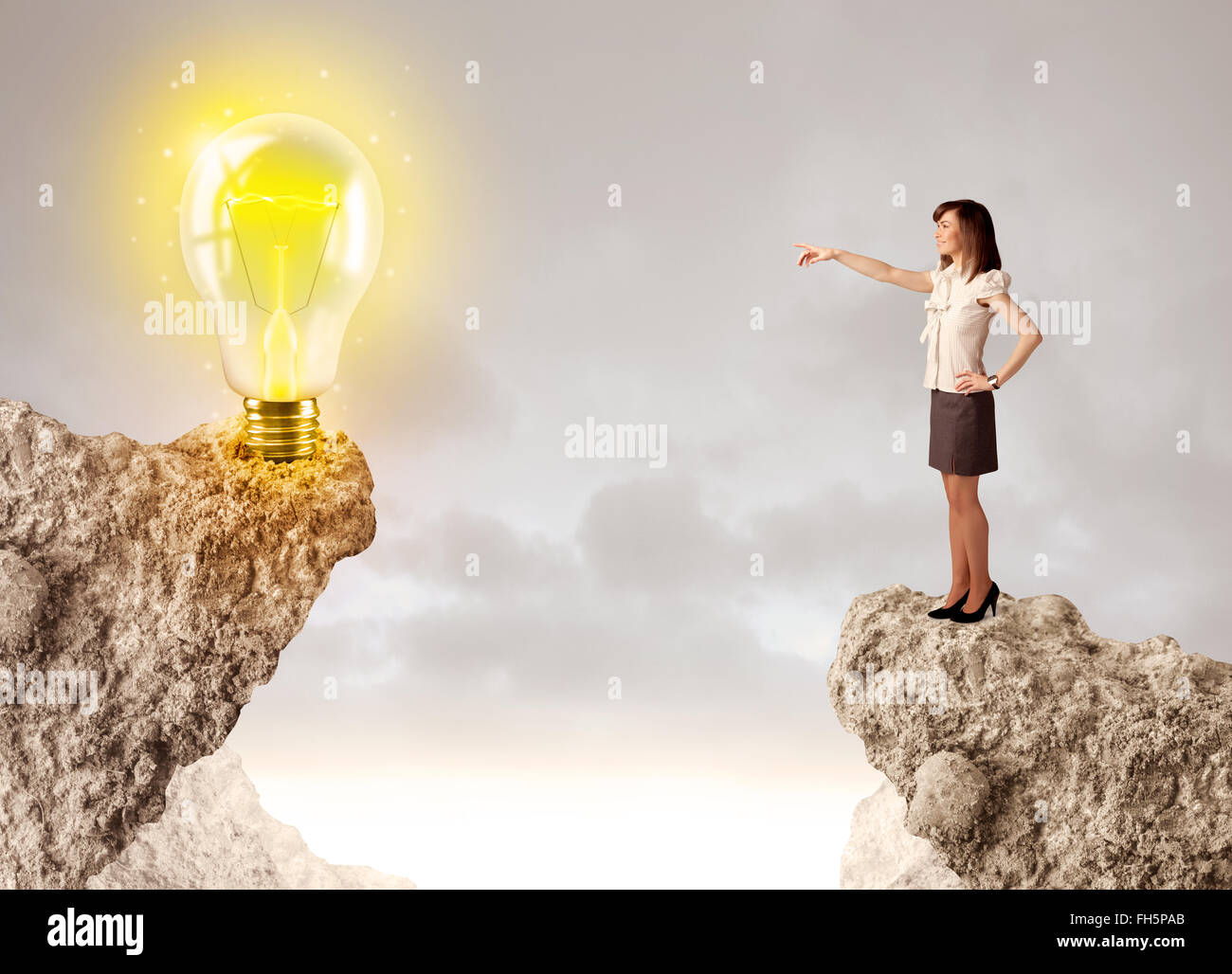 Businesswoman on rock mountain with idea bulb Stock Photo