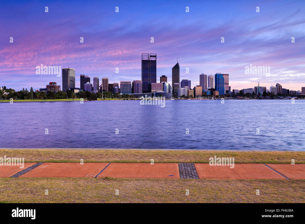 panoramic view of skyscrapers in Perth, Western Australia, across Swan river at sunrise. Walking trail in background. Stock Photo